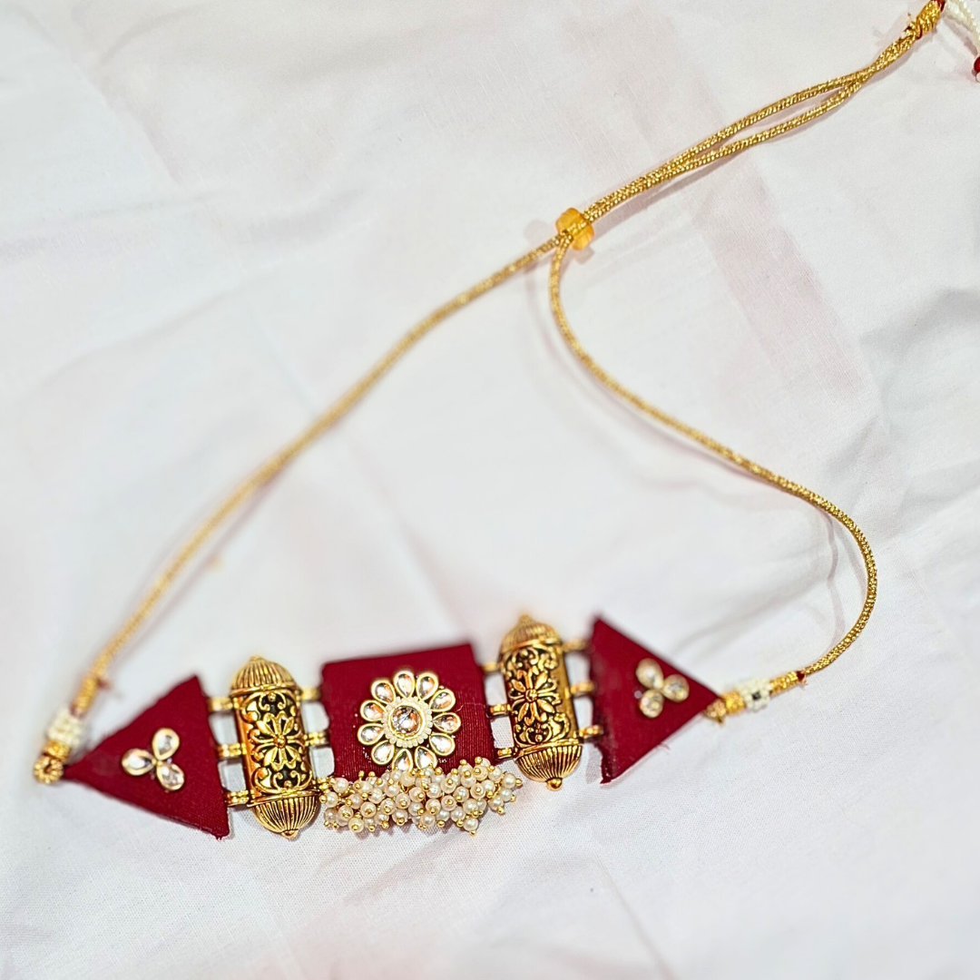 Handcrafted gold and maroon ethnic necklace with pearl accents on white background