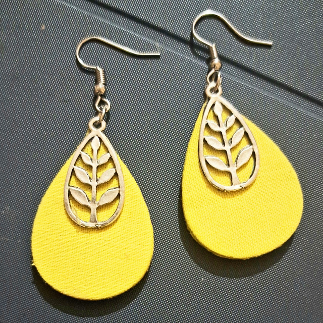 Yellow teardrop earrings with silver leaf design on textured background
