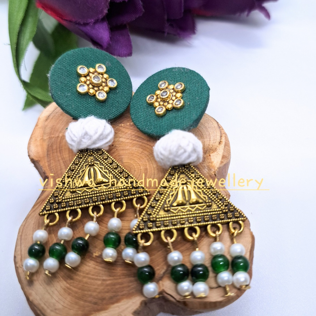 Handmade green and gold triangle earrings with pearls and bead details on wooden display