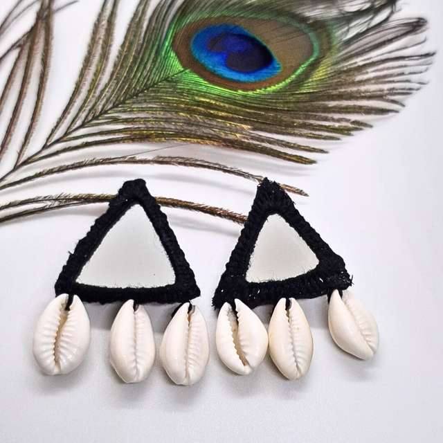Handcrafted triangle mirror earrings with black border and cowrie shells, peacock feather background