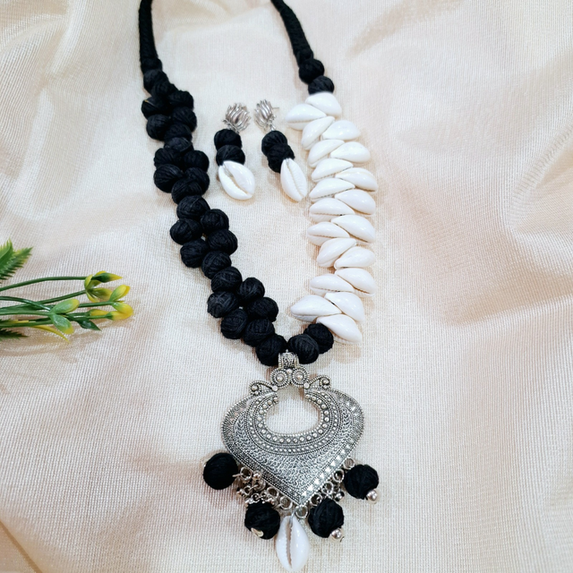 Handcrafted black and white shell and fabric necklace set with ornate silver pendant and earrings