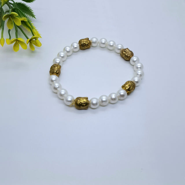 White pearl beaded bracelet with gold Buddha beads on a white background, floral accent