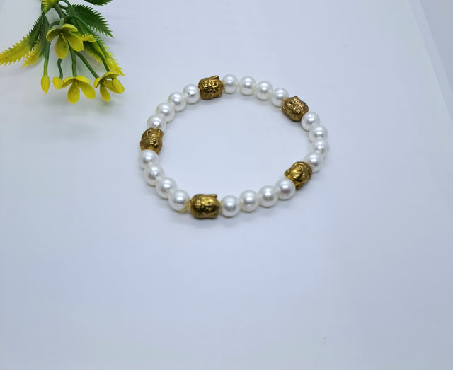 White pearl beaded bracelet with gold Buddha beads on a white background, floral accent